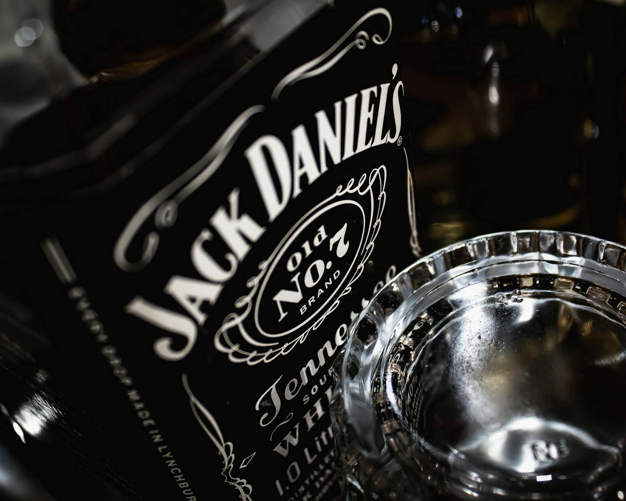 brand-03 Detailed view of a Jack Daniels whiskey bottle with glass, highlighting the brands iconic label.
