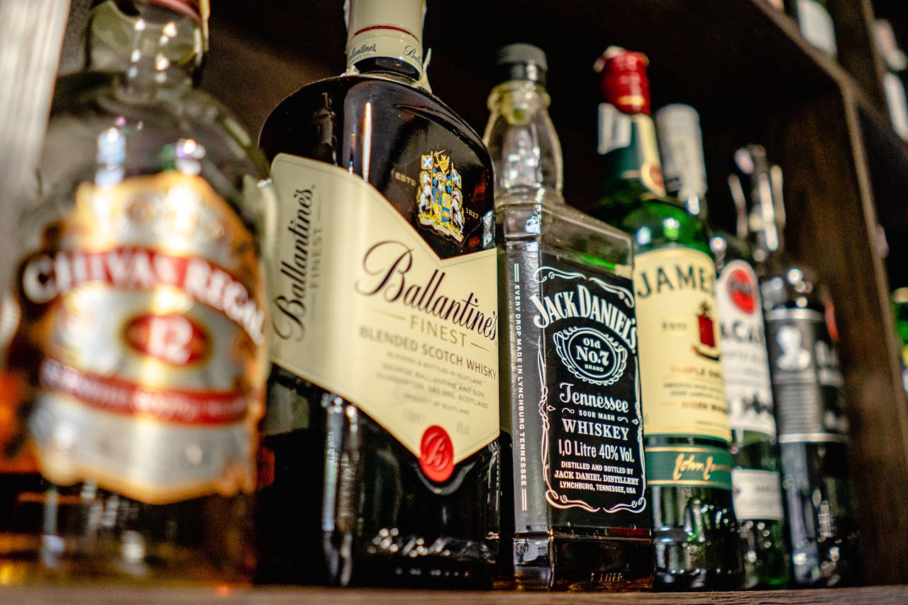 creative-03 Close-up of various whiskey bottles on a bar shelf showcasing popular brands.