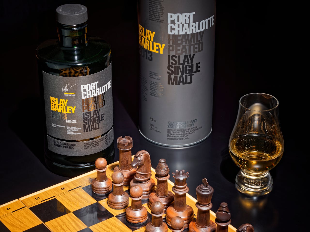 Elegant still life featuring a chessboard and Port Charlotte whisky.