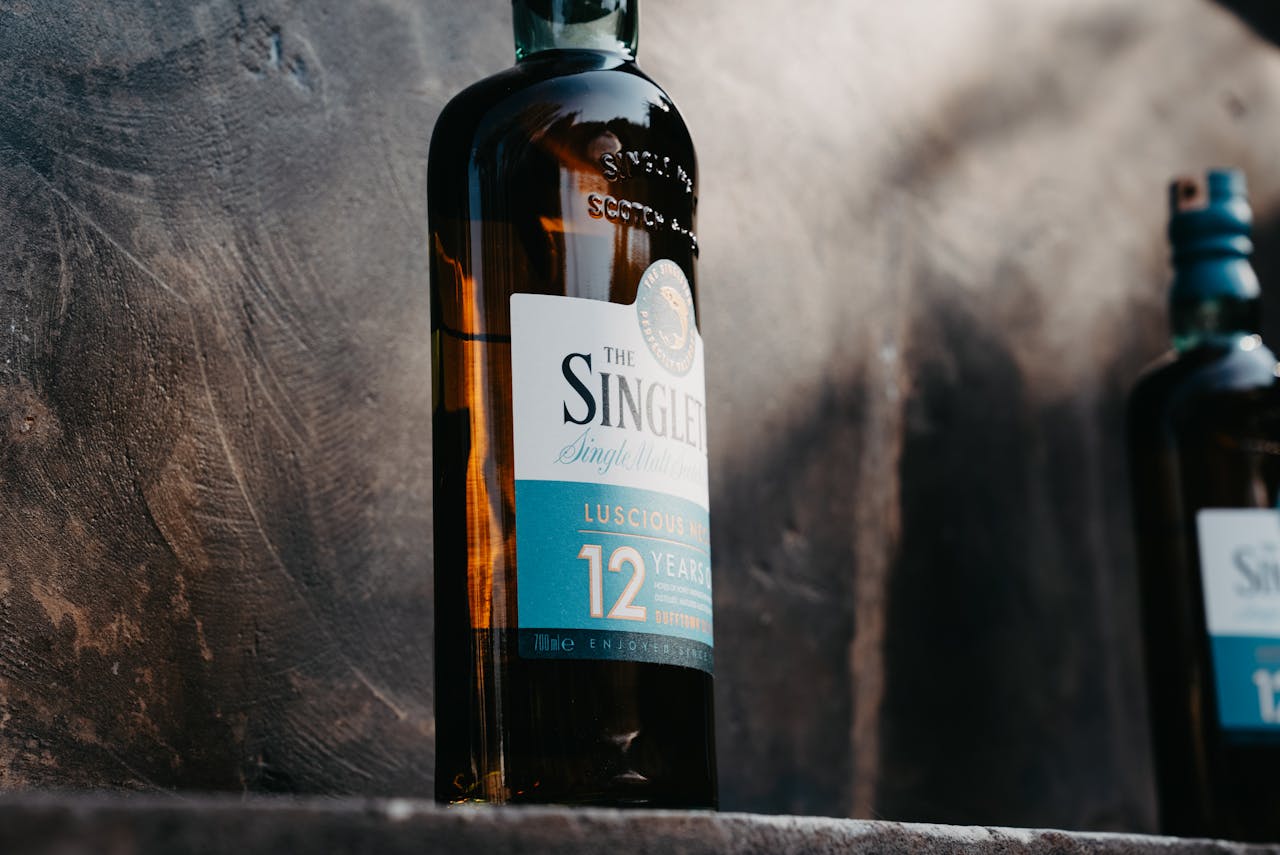 brand-01 Close-up of a 12-year-old single malt whisky bottle with elegant design on a textured background.