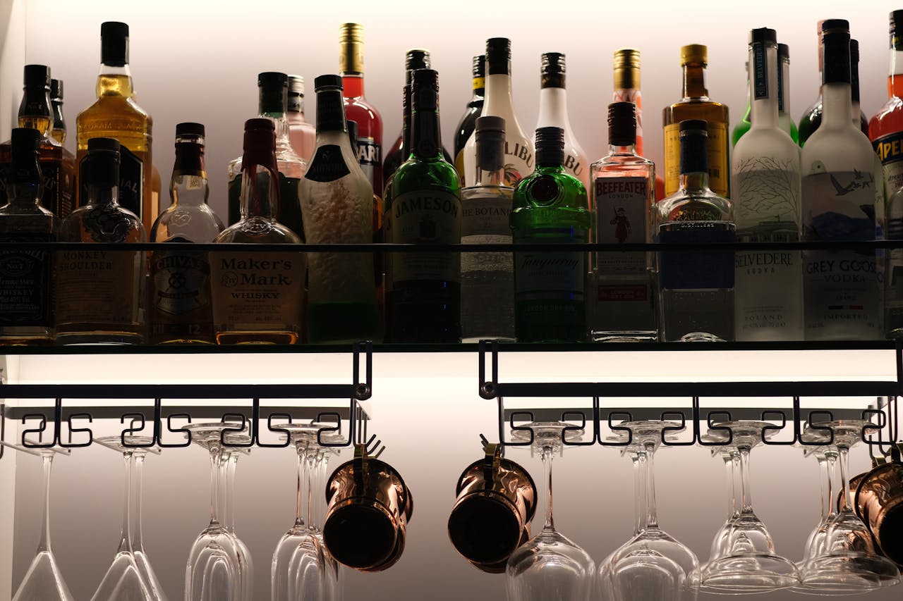 creative-03 A stylish and organized display of assorted liquor bottles on a bar shelf with hanging glassware below.